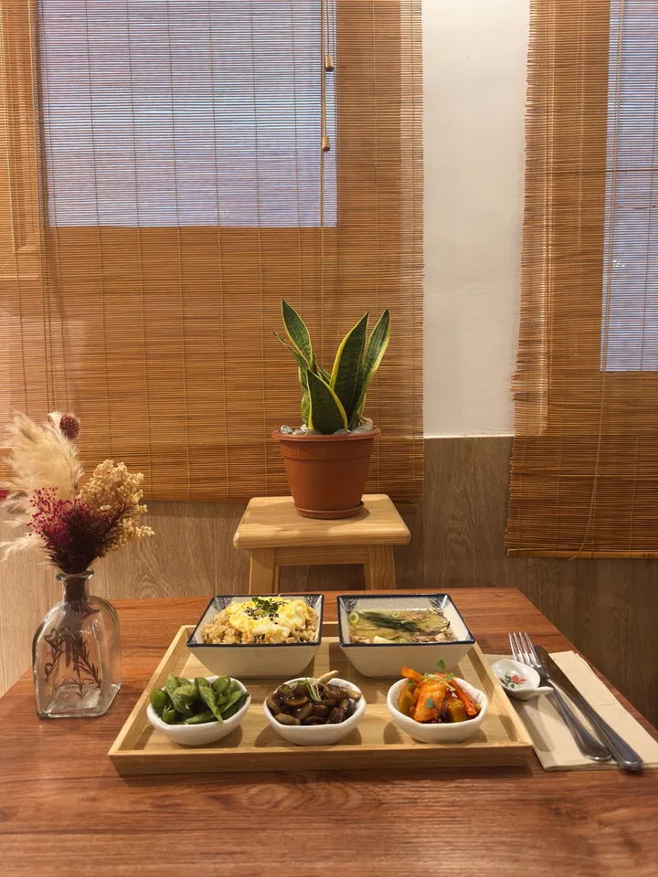 The lunch set on a wooden tray: fried rice with egg, miso soup, edamame, mushrooms and kimchi