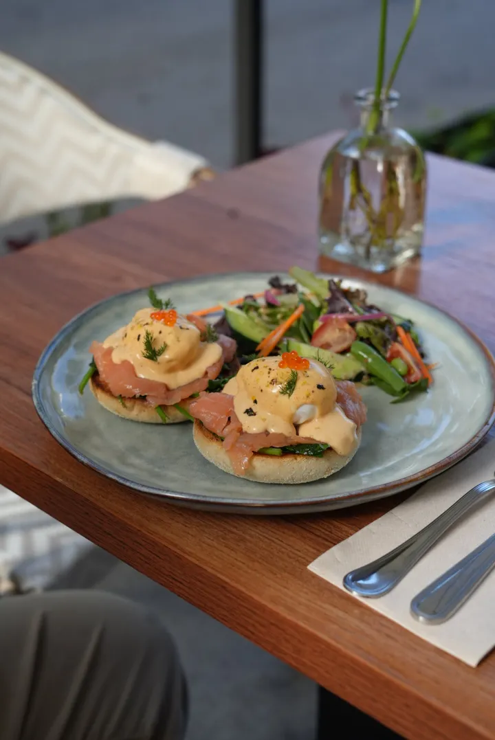 Salmon Benny with yuzu hollandaise and a green salad, on a terrace table