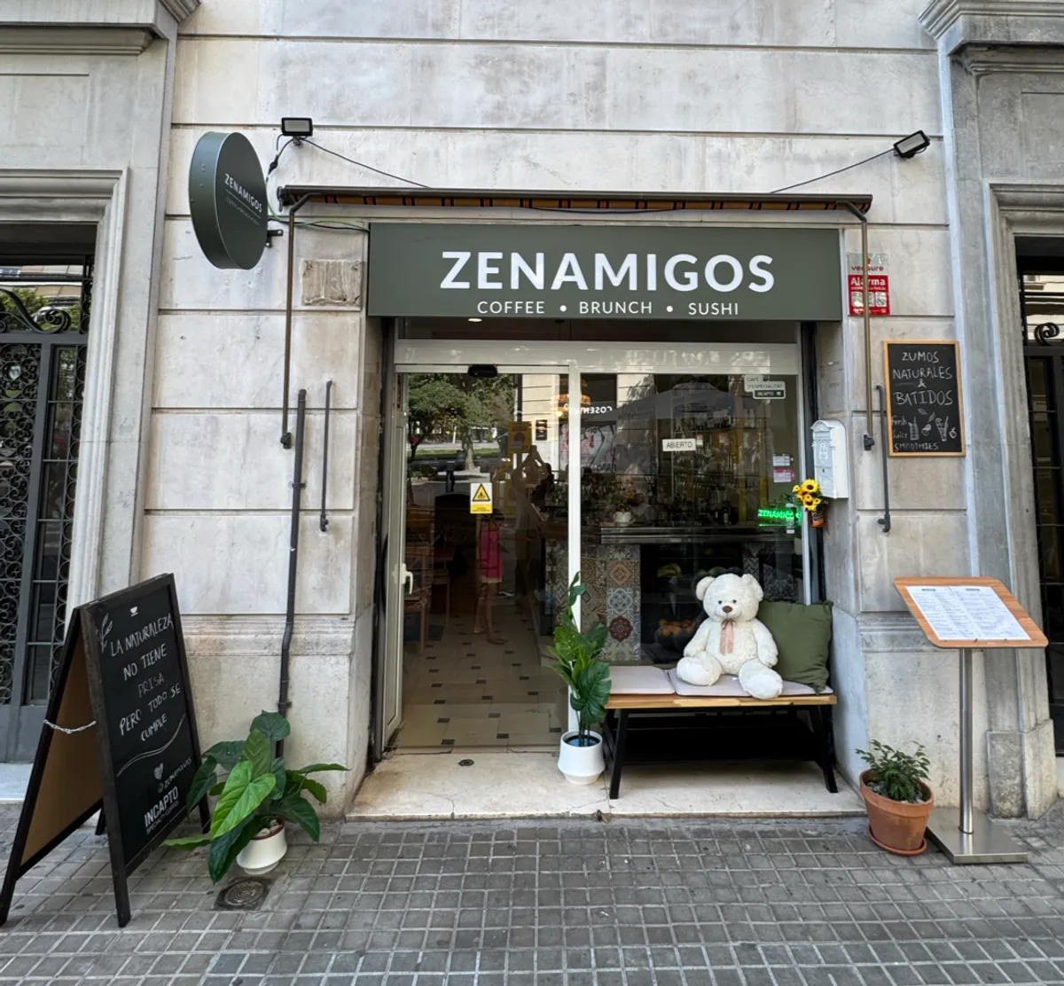 The ZENAMIGOS building on Carrer de Loreto, with the green sign and the terrace