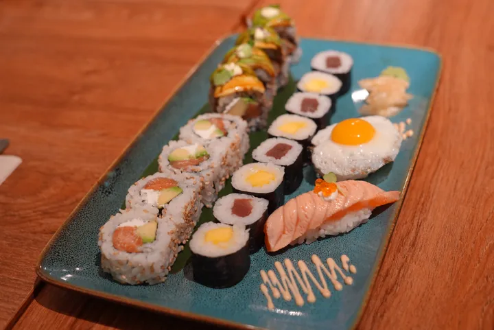 The Zen signature platter on a blue plate: maki, Dragon roll, salmon roll, quail egg nigiri and salmon nigiri