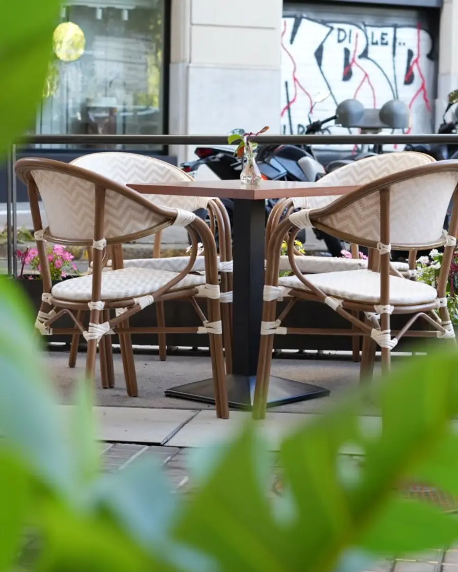 Cadires de vímet a la terrassa del carrer, vistes entre fulles